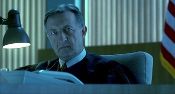 Movie still from “I Am Sam” (2001), directed by Jessie Nelson – An older man sitting in a chair in a courtroom; Close Up shot, Low angle