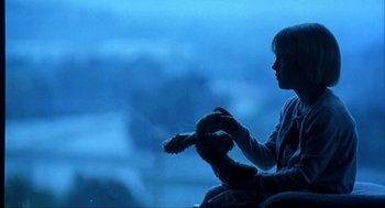 Movie still from “I Am Sam” (2001), directed by Jessie Nelson – A child holding a teddy bear in a dark room; Medium shot, Over the shoulder angle