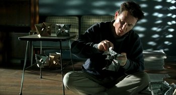 Movie still from “I Am Sam” (2001), directed by Jessie Nelson – A man sitting on the ground holding a paper windmill; Medium shot, High angle