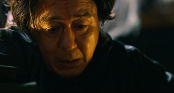 Movie still from “I Saw the Devil” (2010), directed by Jee-woon Kim – An older man looking down at the ground; Close Up shot, Low angle