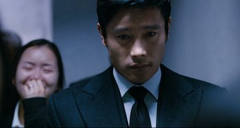 Movie still from “I Saw the Devil” (2010), directed by Jee-woon Kim – A man wearing a suit and tie standing next to a woman; Close Up shot, Over the shoulder angle