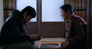 Movie still from “I Saw the Devil” (2010), directed by Jee-woon Kim – A man and a woman looking at a cell phone; Medium shot, Over the shoulder angle