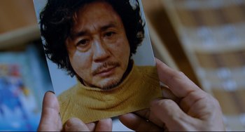 Movie still from “I Saw the Devil” (2010), directed by Jee-woon Kim – A person holding a picture of a man; Extreme Close Up shot, High angle