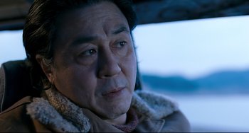 Movie still from “I Saw the Devil” (2010), directed by Jee-woon Kim – An older man wearing a jacket and a scarf; Close Up shot, Low angle