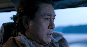 Movie still from “I Saw the Devil” (2010), directed by Jee-woon Kim – An older man in a brown jacket looking at the camera; Close Up shot, Low angle