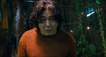 Movie still from “I Saw the Devil” (2010), directed by Jee-woon Kim – A man in an orange sweater looking at the camera; Close Up shot, Low angle