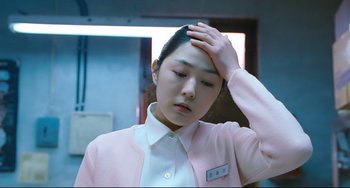 Movie still from “I Saw the Devil” (2010), directed by Jee-woon Kim – A woman in a white shirt and pink jacket holding her hand to her head; Close Up shot, Low angle