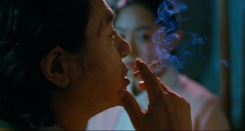 Movie still from “I Saw the Devil” (2010), directed by Jee-woon Kim – A man smoking a cigarette while a woman looks on; Close Up shot, Over the shoulder angle