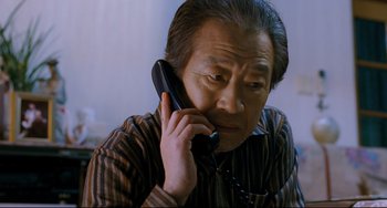 Movie still from “I Saw the Devil” (2010), directed by Jee-woon Kim – An older man talking on a phone while sitting down; Close Up shot, Low angle