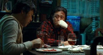 Movie still from “I Saw the Devil” (2010), directed by Jee-woon Kim – A man sitting at a table with a glass of red wine; Medium shot, Over the shoulder angle