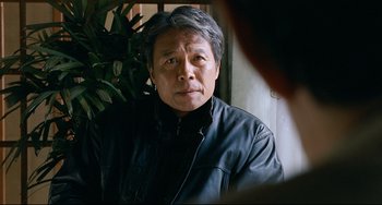 Movie still from “I Saw the Devil” (2010), directed by Jee-woon Kim – An older man wearing a leather jacket looking at the camera; Close Up shot, Over the shoulder angle