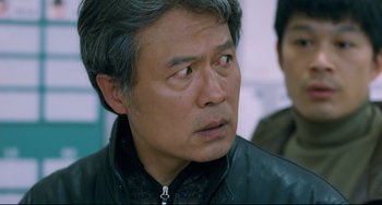 Movie still from “I Saw the Devil” (2010), directed by Jee-woon Kim – An older man wearing a leather jacket looking to his left; Close Up shot, Over the shoulder angle