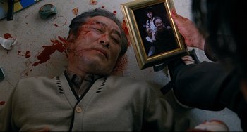 Movie still from “I Saw the Devil” (2010), directed by Jee-woon Kim – A man holding up a picture with blood on his face; Close Up shot, Overhead angle