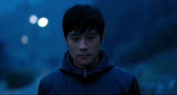 Movie still from “I Saw the Devil” (2010), directed by Jee-woon Kim – A young man in a blue jacket is looking at the camera; Close Up shot, High angle
