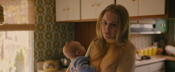 Movie still from “I'm Your Woman” (2020), directed by Julia Hart – A woman holding a baby in her arms in a kitchen; Close Up shot, Over the shoulder angle