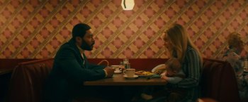 Movie still from “I'm Your Woman” (2020), directed by Julia Hart – A man and a woman sitting at a table with food; Medium shot, High angle