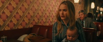 Movie still from “I'm Your Woman” (2020), directed by Julia Hart – A woman holding a baby in her arms and looking at the camera; Close Up shot, Over the shoulder angle