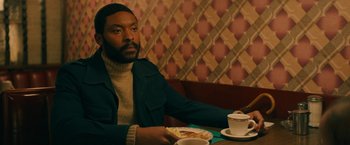 Movie still from “I'm Your Woman” (2020), directed by Julia Hart – A man sitting at a table with a plate of food in front of him; Medium shot, Low angle