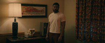 Movie still from “I'm Your Woman” (2020), directed by Julia Hart – A man standing in front of a tv in a living room; Medium shot, Low angle