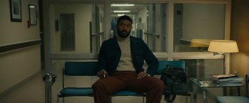 Movie still from “I'm Your Woman” (2020), directed by Julia Hart – A man sitting on top of a bench in a room; Medium shot, Low angle