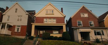 Movie still from “I'm Your Woman” (2020), directed by Julia Hart – A yellow and red house with a green roof; Extreme Wide shot, Low angle
