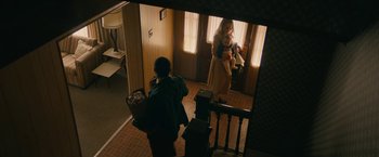 Movie still from “I'm Your Woman” (2020), directed by Julia Hart – A woman holding a baby in her arms while standing in front of a mirror; Wide shot, High angle