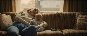 Movie still from “I'm Your Woman” (2020), directed by Julia Hart – A woman sitting on a couch with a baby on her lap; Medium shot, High angle