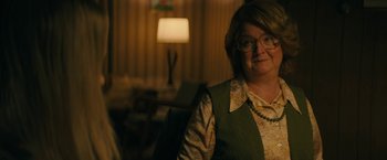 Movie still from “I'm Your Woman” (2020), directed by Julia Hart – A woman in glasses and a green vest sitting in front of a lamp; Close Up shot, Over the shoulder angle