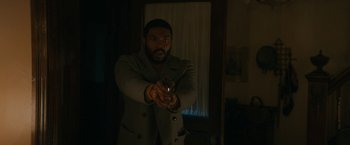 Movie still from “I'm Your Woman” (2020), directed by Julia Hart – A man holding a gun in a dark room; Medium shot, Over the shoulder angle