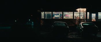 Movie still from “I'm Your Woman” (2020), directed by Julia Hart – A car parked in front of an open sign; Extreme Wide shot, Over the shoulder angle