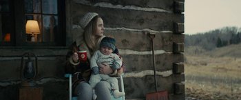 Movie still from “I'm Your Woman” (2020), directed by Julia Hart – A woman holding a baby while sitting on a chair; Medium shot, Over the shoulder angle