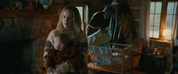 Movie still from “I'm Your Woman” (2020), directed by Julia Hart – A woman holding a baby in her arms in front of a crib; Medium shot, Over the shoulder angle