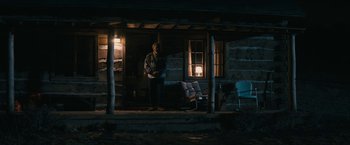 Movie still from “I'm Your Woman” (2020), directed by Julia Hart – A man standing on the porch of a log cabin at night; Wide shot, Low angle