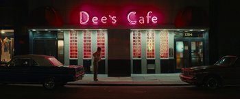 Movie still from “I'm Your Woman” (2020), directed by Julia Hart – A person standing outside of a cafe at night; Extreme Wide shot, Low angle