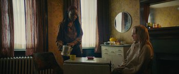 Movie still from “I'm Your Woman” (2020), directed by Julia Hart – A woman pouring a cup of tea into a mug; Medium shot, Over the shoulder angle