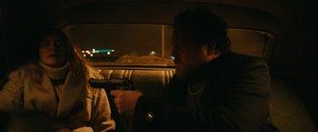 Movie still from “I'm Your Woman” (2020), directed by Julia Hart – A man holding a gun while sitting in the back of a car; Medium shot, Over the shoulder angle
