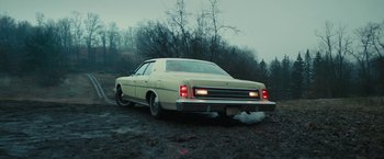 Movie still from “I'm Your Woman” (2020), directed by Julia Hart – An old car is parked on the side of the road; Wide shot, High angle