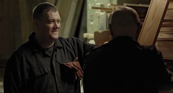 Movie still from “I, Daniel Blake” (2016), directed by Ken Loach – A man standing next to another man in a room; Medium shot, Over the shoulder angle