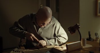 Movie still from “I, Daniel Blake” (2016), directed by Ken Loach – An older bald man in a gray sweatshirt working with wood; Medium shot, Low angle