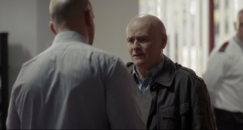 Movie still from “I, Daniel Blake” (2016), directed by Ken Loach – Two men standing next to each other in front of a window; Medium shot, Over the shoulder angle