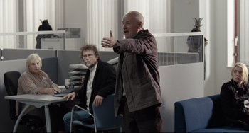 Movie still from “I, Daniel Blake” (2016), directed by Ken Loach – A man in a brown jacket is talking to a man in a black jacket; Medium shot, Over the shoulder angle