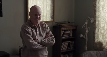 Movie still from “I, Daniel Blake” (2016), directed by Ken Loach – An older man standing in front of a book case; Medium shot, Over the shoulder angle