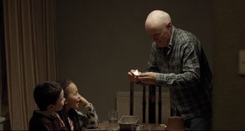 Movie still from “I, Daniel Blake” (2016), directed by Ken Loach – An older man holding a candle near two young children; Medium shot, Over the shoulder angle