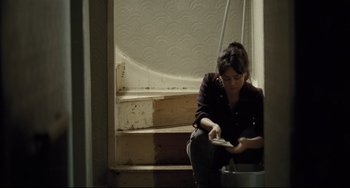 Movie still from “I, Daniel Blake” (2016), directed by Ken Loach – A woman sitting on the steps looking at her cell phone; Medium shot, High angle