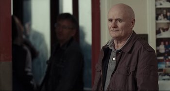 Movie still from “I, Daniel Blake” (2016), directed by Ken Loach – A man with a bald head standing in front of a mirror; Medium shot, Over the shoulder angle