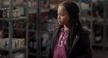 Movie still from “I, Daniel Blake” (2016), directed by Ken Loach – A young girl with long braids looking to her left; Close Up shot, Over the shoulder angle