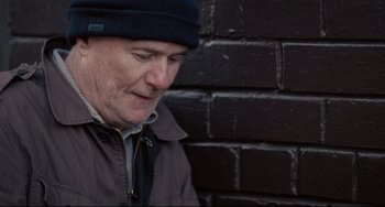 Movie still from “I, Daniel Blake” (2016), directed by Ken Loach – A person wearing a jacket and a hat; Close Up shot, Over the shoulder angle