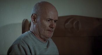 Movie still from “I, Daniel Blake” (2016), directed by Ken Loach – An older man sitting on a couch looking at the camera; Close Up shot, Low angle