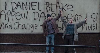 Movie still from “I, Daniel Blake” (2016), directed by Ken Loach – Two men standing in front of a wall covered in graffiti; Wide shot, Overhead angle