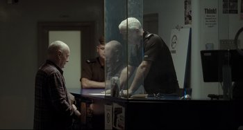 Movie still from “I, Daniel Blake” (2016), directed by Ken Loach – A man standing in front of two other men in a room; Medium shot, Over the shoulder angle
